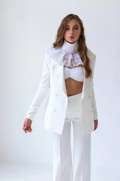 Young blonde girl in white suit and jabot on white background