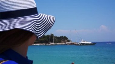 Deniz sahilinde kızıl saçlı kadın denizde izliyor.