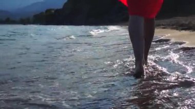 Arka planda dağlar ile kumlu bir plajda deniz dalgaları.