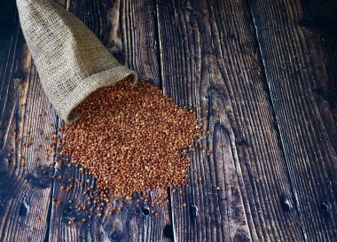 Tahta bir masaya çuval bezinden karabuğday taneleri dökülüyor..