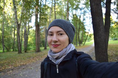 Slav tipli genç bir kadın şehir parkında yürüyor ve doğaya hayranlık duyuyor, mesafeye dalgın dalgın bakıyor, doğaya hayranlık duyuyor, doğaya hayranlık duyuyor. Sarı saçlı, örgülü genç bir kadın..