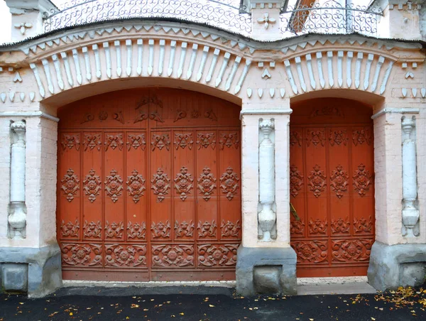 Carved antique gate and doors to a stone mansion. Folk crafts.  Delicate wood carving with plant motifs. Emergency entrance to the administration of the city of Alapaevsk, Sverdlovsk region, Russia.