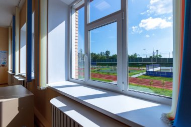 Spor alanına bakan bir okul penceresinden mavi gökyüzü