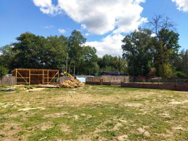 A rural construction site shows wooden framework progress.