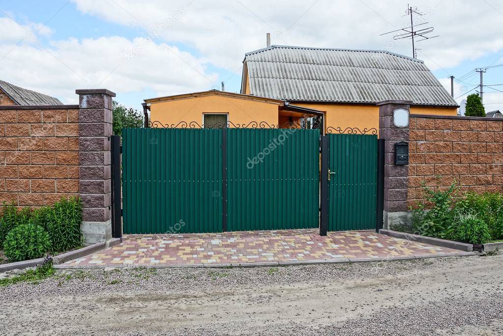 iron gate is green and part of the brown fence is on the street
