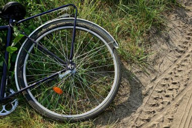 bir bisiklet tekerleği ile parçası road yakınındaki çimenlerin üzerinde yatıyor