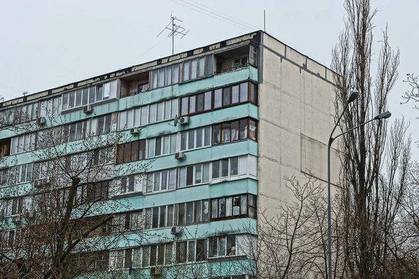 part of a tall house with balconies and windows on a background of trees and sky