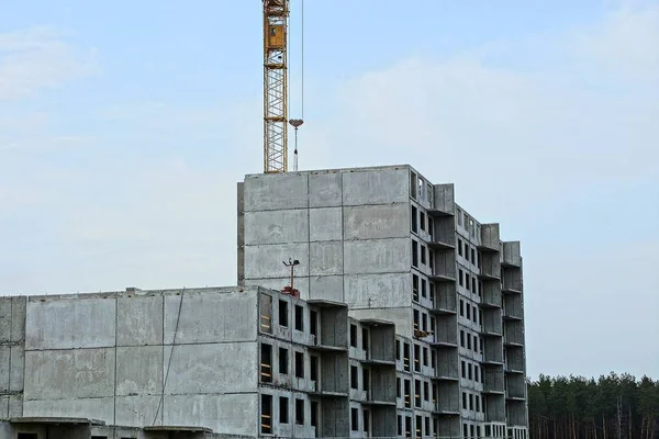 unfinished tall house with a tower crane against the sky