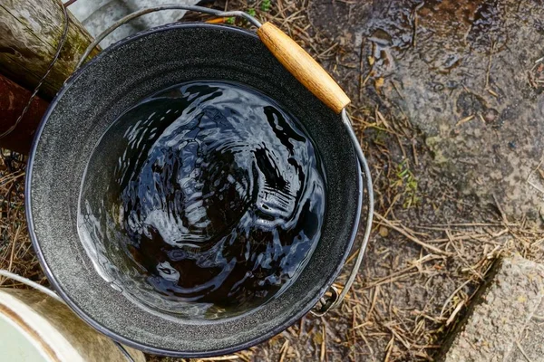 a black bucket full of water is standing on the street