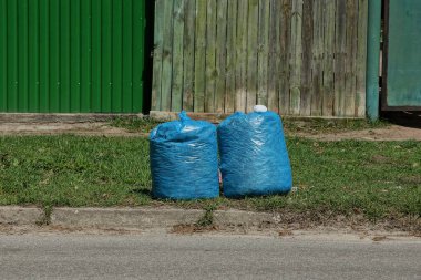 yolun iki mavi plastik torbalar çöp yeşil çimenlerin üzerinde yakın: