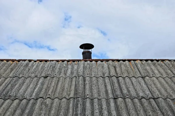 part of an old gray slate roof pipe on a sky and clouds background