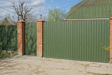 bir uzun demir çit yeşil renk ve yolun yakınlarında sokakta kapalı bir kapı parçası