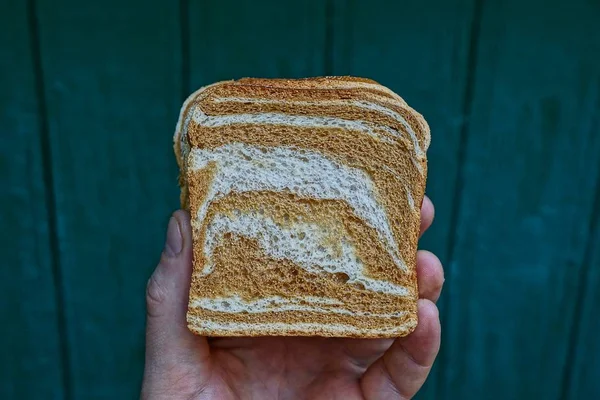 Stück Eckiges Brot Der Hand Auf Grünem Hintergrund — Stockfoto