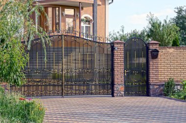 büyük metal bir kapı ve bir kahverengi tuğla çit sokak