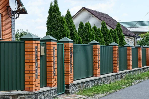 Fence and gate made of metal and bricks on the street near the road