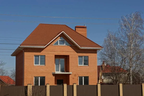 砖私有褐色房子在篱芭之后在天空背景 — 图库照片