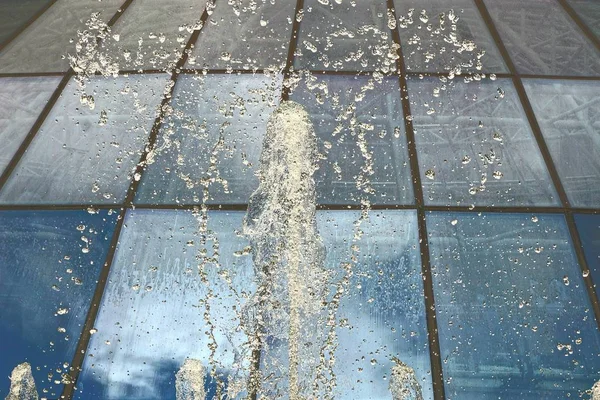 Spruzzando Acqua Una Fontana Uno Sfondo Parete Vetro — Foto Stock