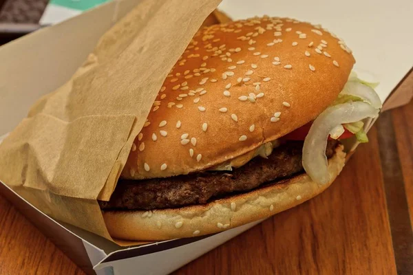 brown cheeseburger in paper packing on the table