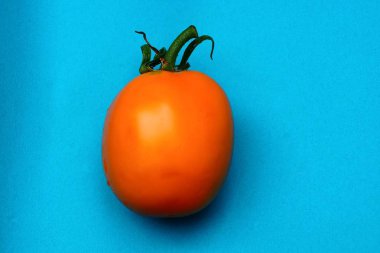 büyük bir taze sarı domates mavi bir masada yatıyor