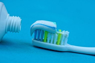 üzerinde mavi bir tablo üzerinde beyaz bir tüp karşı bir diş fırçası diş macunu