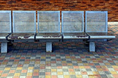 Duvarın yanında kaldırımda eski gri metal koltuk standı