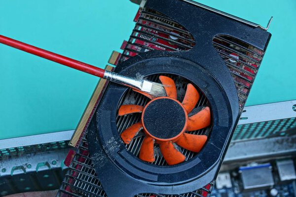 the old video card in the dust is cleaned with a red brush