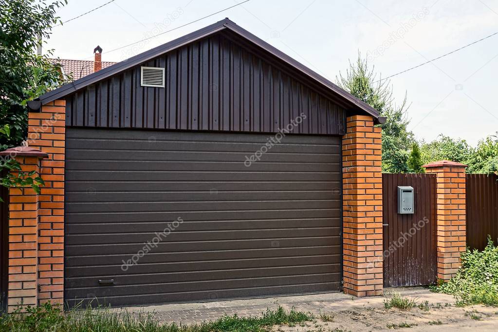 Private house with closed brown gates and a fence in a rural street