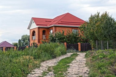 yeşil çim çit dışında bir büyük kırmızı ev önünde yolundaki