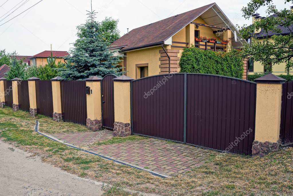 brown iron closed gates and part of a long brick fence in the street 
