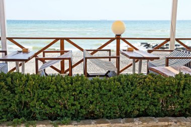 Masa ve sandalyeler ile plaj restoran terasında bir yeşil çiçek yatak