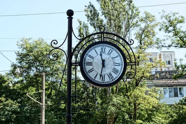 large round clock on a black column in the park