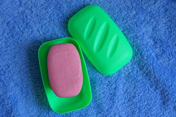 绿色塑料肥皂盘用红色肥皂在蓝色布料毛巾 — 图库照片