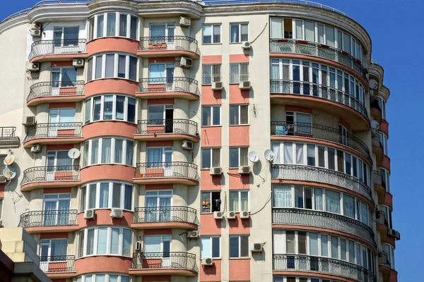 part of a large gray brown house with balconies and windows on the sky background