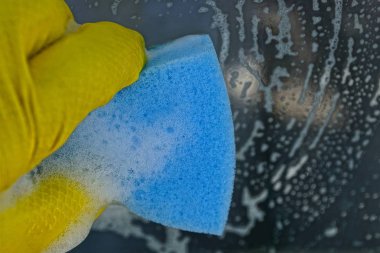 Sarı bir eldiven elinde bir mavi sünger pencere yıkar