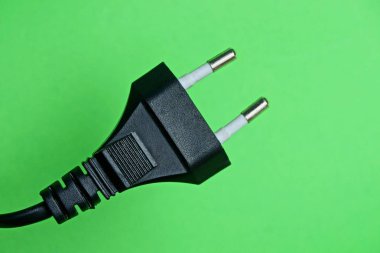 Tel yeşil bir arka plan üzerinde siyah elektrik fiş