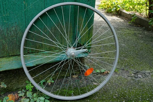 ねずみ鋳鉄通りに緑の木製の壁の近くの自転車の車輪の縁 — ストック写真