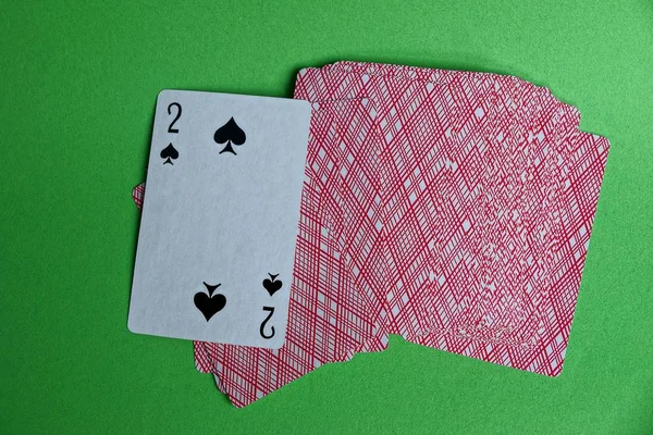 a deck of red cards with a peak deuce on a green table