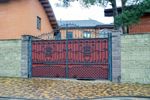 在街道上的一个锻造图案和一个长石栅栏的私人红铁门 — 图库照片