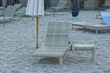 gri tembel ve sahilde kum kaplı bir şemsiye