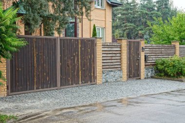 kahverengi çit ve ahşap bir kapı ve yolun yakınında sokakta bir kapı