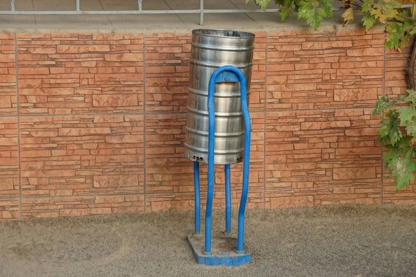 Uma Urna Metal Fica Asfalto Perto Parede Tijolo — Fotografia de Stock