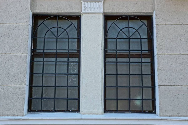 灰色混凝土墙上有格子的两个褐色窗户 — 图库照片