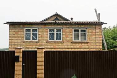 yeşil bitki örtüsü sokakta bir kapı ile çit arkasında penceresi olan büyük özel ev