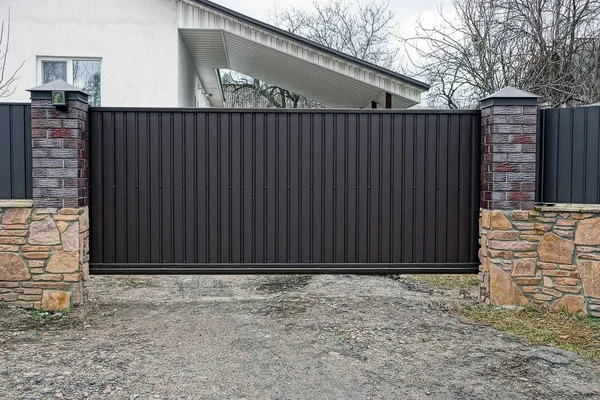 Büyük kapalı kahverengi gates ve çit sokakta bir parçası