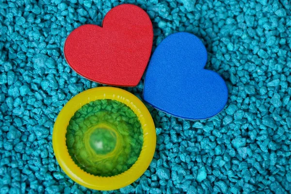 Rotes Und Blaues Herz Und Gelbes Kondom Auf Kleinen Steinen — Stockfoto