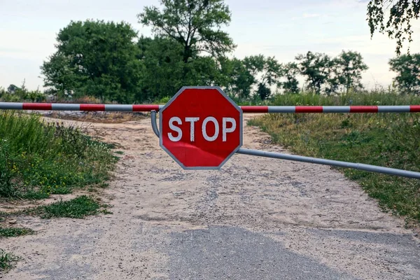 A barrier with a road sign blocks the road and prohibits the passage