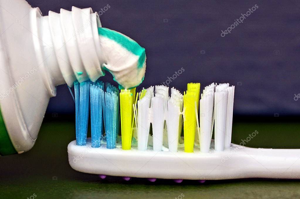 Tube with colored toothpaste and part of toothbrush