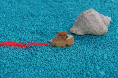 bir kabuk ile kum üzerinde bir oyuncak tekne yelken