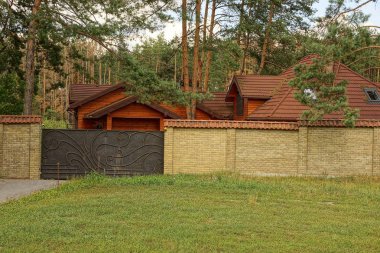 Iron gate ve kahverengi tuğla çit dışında yeşil çimen