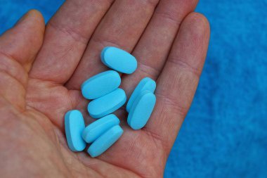 bir avuç mavi hap üzerinde açık el